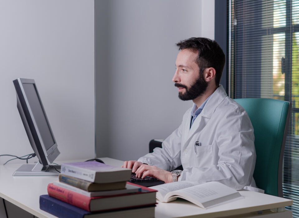 Dott. Gianluca Brunetti - Urologo ed Andrologo nel suo studio durante una visita medica specialstica mentre prescrive la terapia al computer